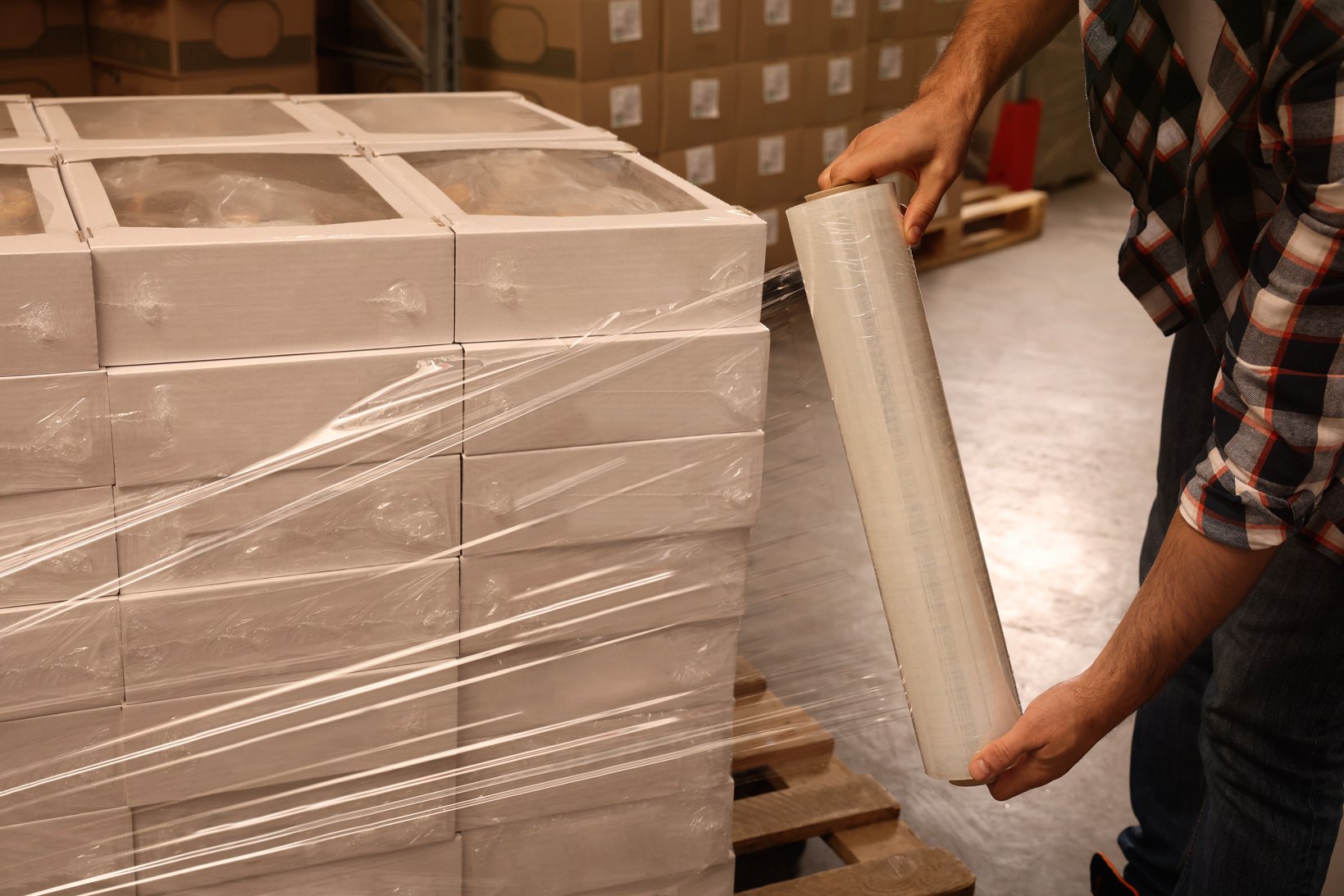 Worker Wrapping Boxes in Stretch Film at Warehouse, Closeup